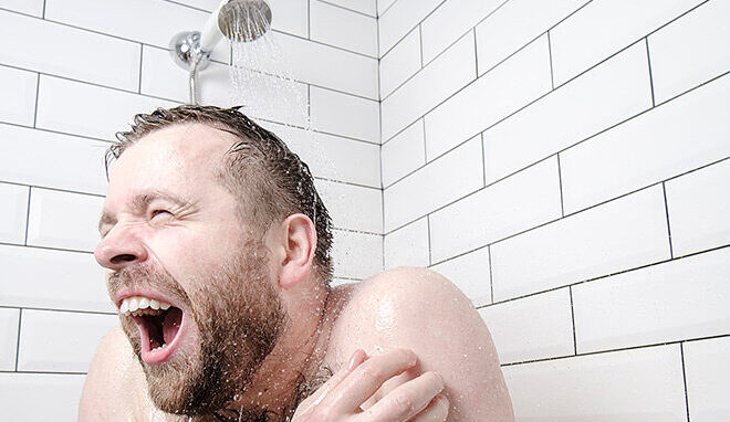 Bearded man taking a cold shower